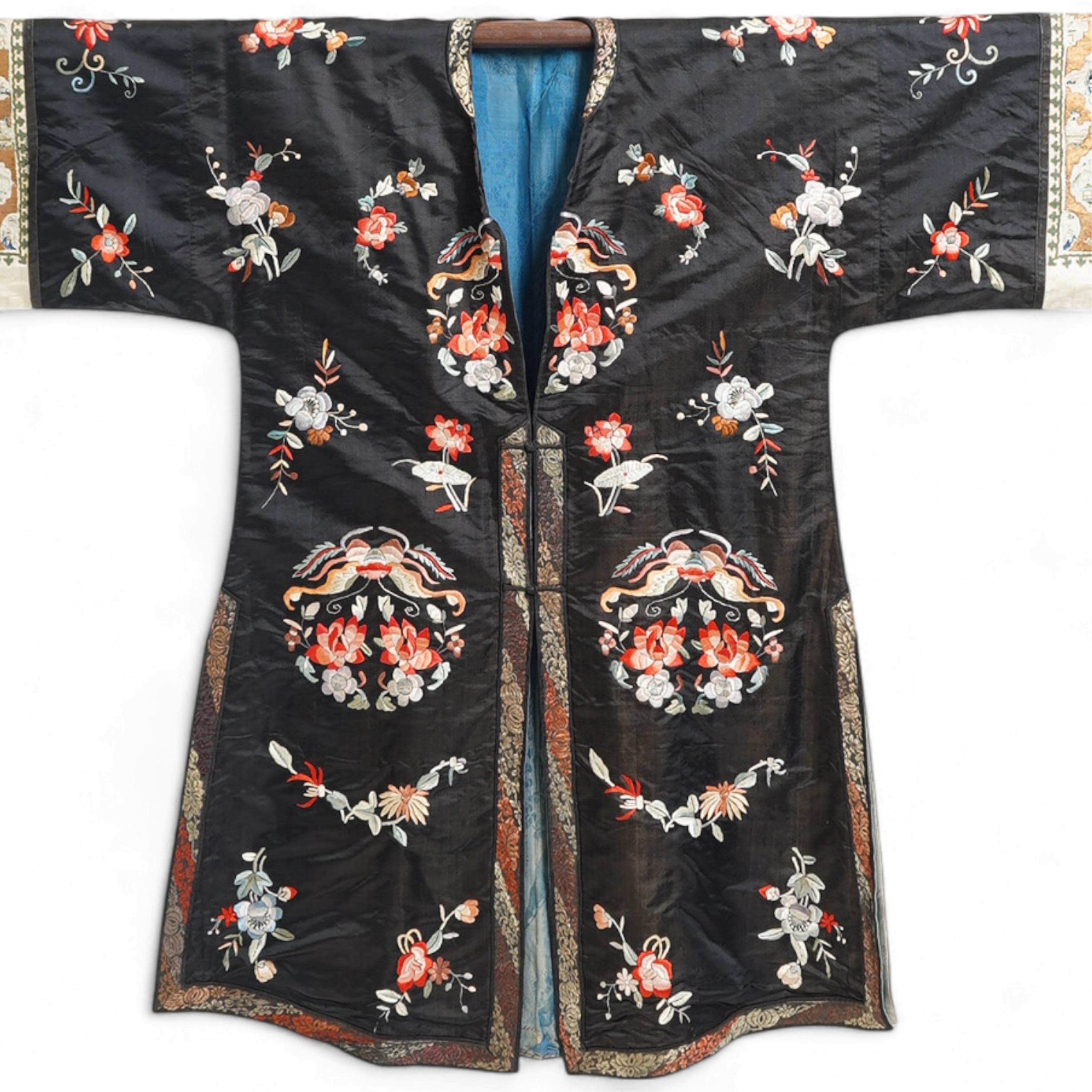 A late 19th early 20th century Chinese black silk polychrome embroidered ladies robe, decorated with cream silk, gilt and Peking knot bordered sleeve bands. The sleeve bands worked with fine figural and other embroidered